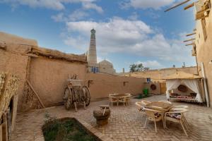 un patio al aire libre con mesas y sillas y una torre en Islam Khodja en Khiva