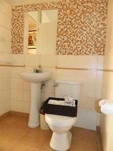y baño con aseo, lavabo y espejo. en Hostal Barranco, en Lima