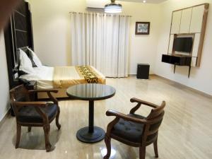 a living room with a bed and a table and chairs at HOTEL NEW ANAND PALACE in Alīgarh
