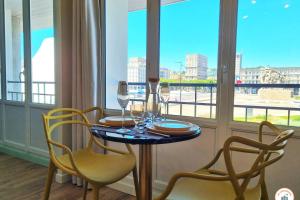 a table with glasses and chairs in a room with a window at The Four Seasons - Panoramic View - Niemeyer Volcano View in Le Havre