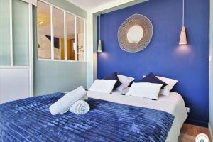 a blue bedroom with a large bed with pillows at The Four Seasons - Panoramic View - Niemeyer Volcano View in Le Havre