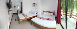 a room with two beds and a balcony at Joyful Guest House in El Nido