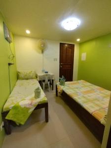 a room with two beds and a table with a table at Joyful Guest House in El Nido