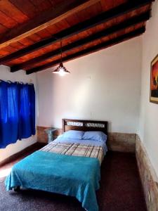 a bedroom with a bed with blue sheets and a wooden ceiling at Hotel La Aparesida in Areguá