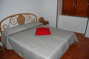 Una cama con una almohada roja encima. en La casa di Anna, en Patti