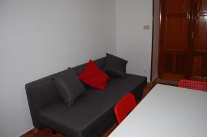 Sofá negro con almohadas rojas en una habitación en La casa di Anna, en Patti