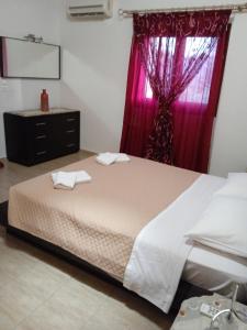 a bedroom with a bed and a window with red curtains at Rouveli Villa with private garden and barbeque in Tragaki