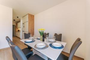 comedor con mesa blanca y sillas en Visit Baltic Apartament Łąkowa 20 en Sarbinowo
