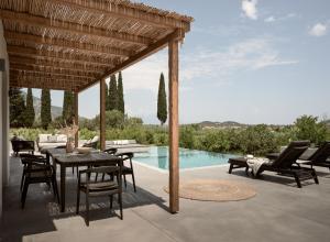 un patio con mesa, sillas y piscina en Yliessa - Luxury pool villa surrounded by nature en Dhrákas