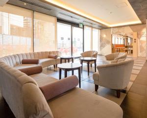 a waiting room with couches and tables and windows at Comfort Hotel Ise in Ise