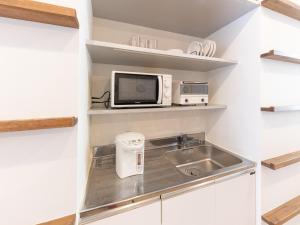 una pequeña cocina con fregadero y microondas en Hiromas Hostel in Ueno, en Tokio