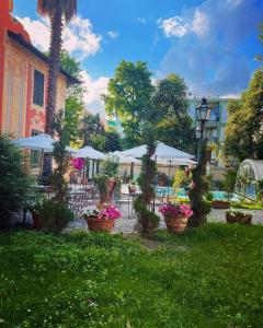 un jardín con macetas, mesas y sombrillas en Villa Mirosa, en Albissola Marina