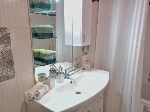 La salle de bains blanche est pourvue d'un lavabo et d'un miroir. dans l'établissement Deluxe Sophia`s Penthouse Apartment, à Karpathos