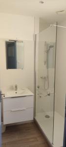 een witte badkamer met een wastafel en een douche bij Le Gabian, duplex proche plage et centre in Sanary-sur-Mer