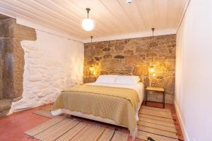 a bedroom with a bed in a stone wall at Quinta do Rio Noémi in Guarda