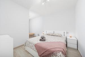 una camera bianca con un grande letto con una coperta rosa di MEDANO4YOU Carpe Diem La Tejita a La Tejita