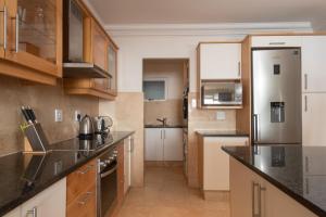 una cocina con armarios de madera y encimeras negras en Ballito Manor View 505 - With Generator, en Ballito