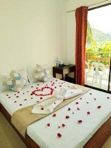 Un dormitorio con una cama con rosas rojas. en Joyful Guest House, en El Nido