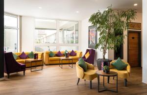 a living room with yellow couches and colorful pillows at DIWOTEL by Trip Inn Frankfurt Airport Dreieich in Dreieich
