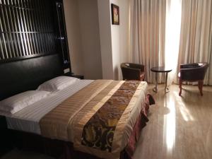 a hotel room with a large bed and chairs at HOTEL NEW ANAND PALACE in Alīgarh