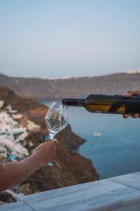 a person is pouring a glass of wine at Oia Captain's Villa in Oia
