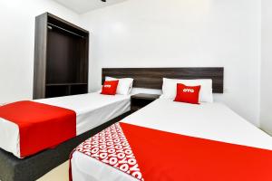 2 camas en una habitación de hotel con almohadas rojas en Super OYO 90509 Usima Forest Resort, en Ayer Keroh