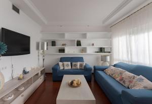 Costa Ballena Unifamiliar في كوستا بالينا: غرفة معيشة مع أريكة زرقاء وتلفزيون