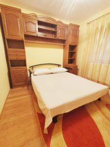 a bedroom with a large bed with wooden cabinets at Apartament Patrick in Curtea de Argeş