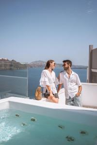 a man and woman sitting on the edge of a bath tub at Oia Captain's Villa in Oia