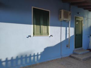 een blauw-wit gebouw met groene ramen en een ventilator bij Da Carla in Iglesias