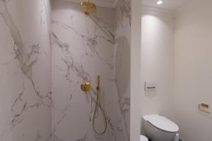 La salle de bains blanche est pourvue d'une douche et de toilettes. dans l'établissement Ankerhus Skagen, à Skagen