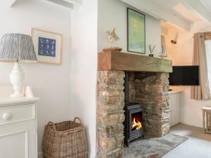 a living room with a stone fireplace with a tv at Oyster Cottage in Salcombe