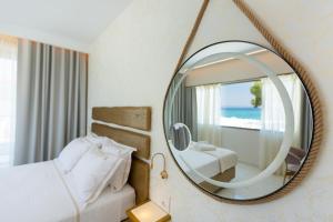 una camera da letto con letto e scrivania e uno specchio di Laguna Resort Boutique Hotel a Hanioti