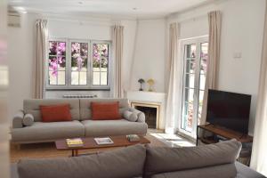 a living room with a couch and a television at Beach house upscale villa with pool in Costa da Caparica