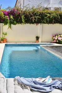 a swimming pool next to a building with flowers at Beach house upscale villa with pool in Costa da Caparica