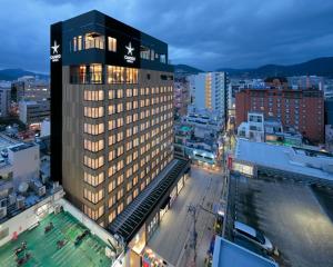 a tall building with a pool in a city at Candeo Hotels Nagasaki Shinchi Chinatown in Nagasaki