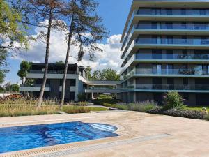 a building with a swimming pool in front of a building at Napfény Resort Apartman in Balatonlelle