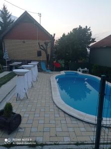 a pool with tables and chairs next to a house at vikendaja in Rakovac