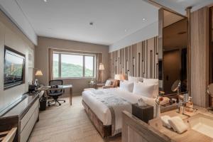 a bedroom with a bed and a desk and a television at Grand Pacific Hotel Ningbo in Yuyao