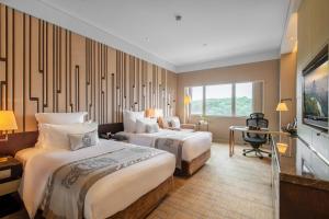 a hotel room with two beds and a desk at Grand Pacific Hotel Ningbo in Yuyao