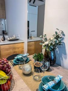 a table with plates and wine glasses on it at Napfény Resort Apartman in Balatonlelle