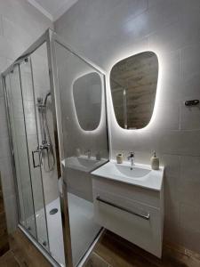 Un baño blanco con lavabo y ducha en Apartments Leona, en Rogoznica