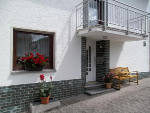 a white building with a balcony and a bench and flowers at Nähe Nürburgring in Quiddelbach, Gästezimmer mit Lounge in Quiddelbach