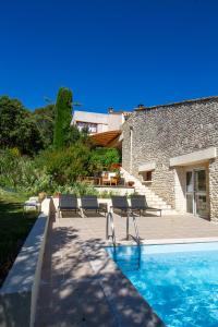 a swimming pool with two chairs and a building at Le Clos des Chênes in Lagarde-Paréol