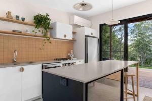 una cucina con mobili bianchi e un piano di lavoro di The Brook View Byron Bay a Ewingsdale Altre 20 foto