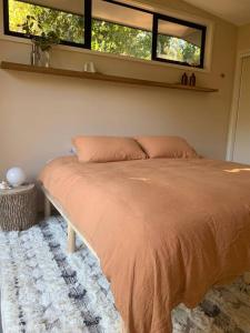 un letto in una camera da letto con due finestre di The Brook View Byron Bay a Ewingsdale