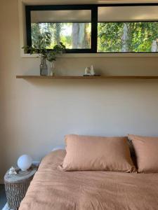 un letto in una camera con finestra e cuscino di The Brook View Byron Bay a Ewingsdale