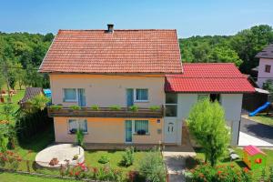 une maison avec un toit rouge et un jardin dans l'établissement Apartman Dorijan, à Rakovica