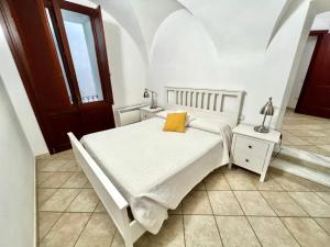 a white bedroom with a bed with a yellow pillow at Sardinian Gallery Corso in Bosa
