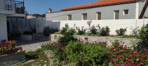 un giardino di fronte a un edificio bianco con fiori di Meraki Skopelos a Panormos Skopelos